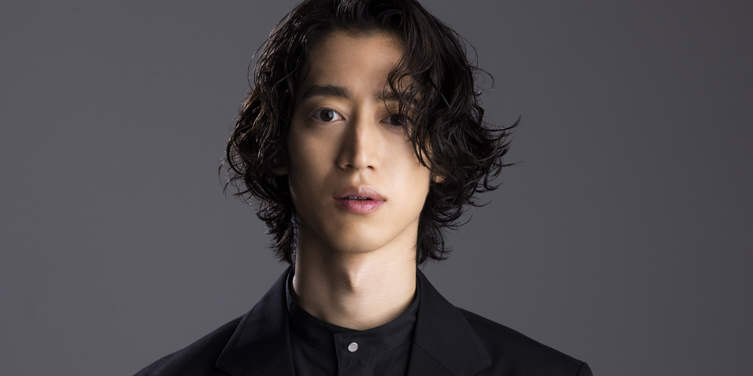 Asian man looks directly at the camera with a neutral expression.