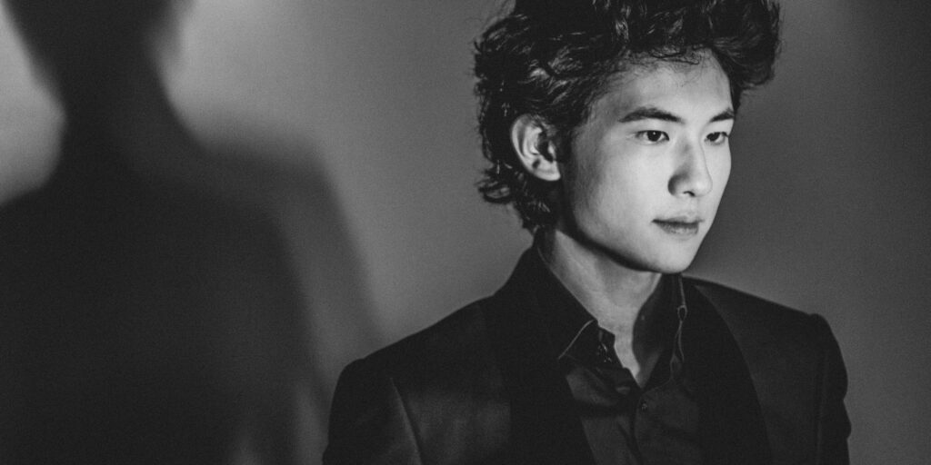 Black and white closeup image of an Asian man looking off to the side.