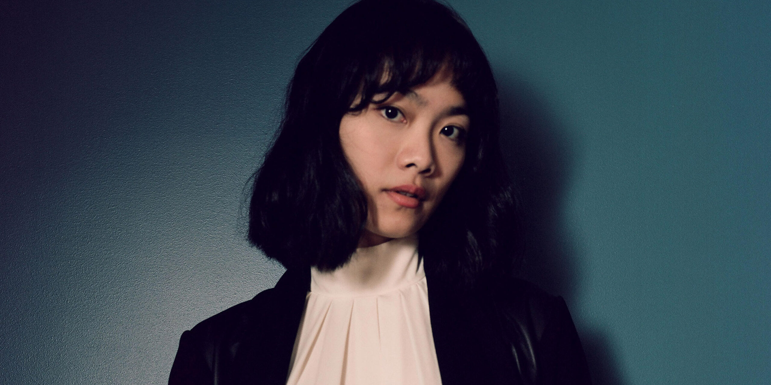 Asian woman posing against a blue backdrop.
